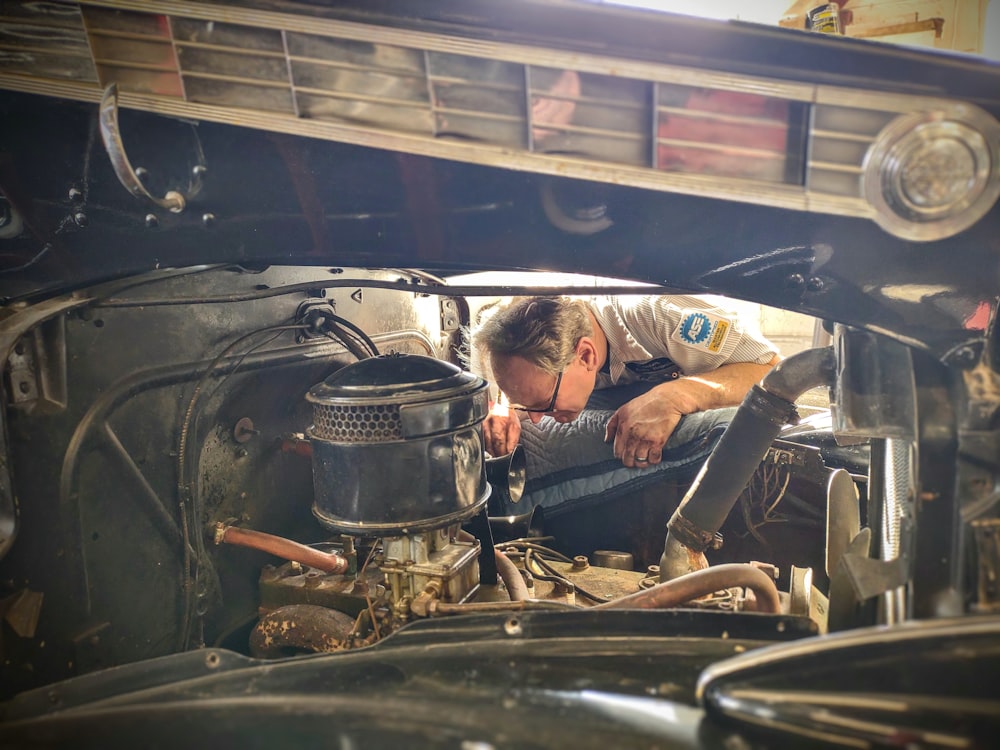 a man working on a car engine in a garage