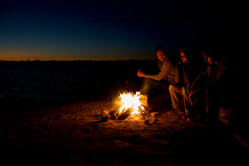 Group of people sitting around a campfire at sunset