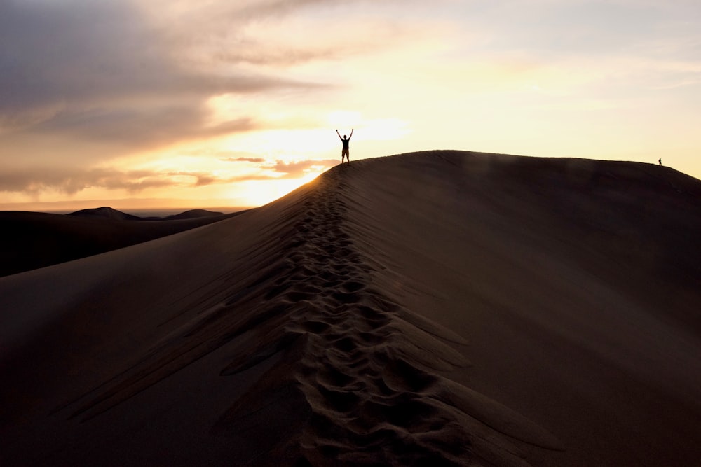 a person standing on top of a sand dune