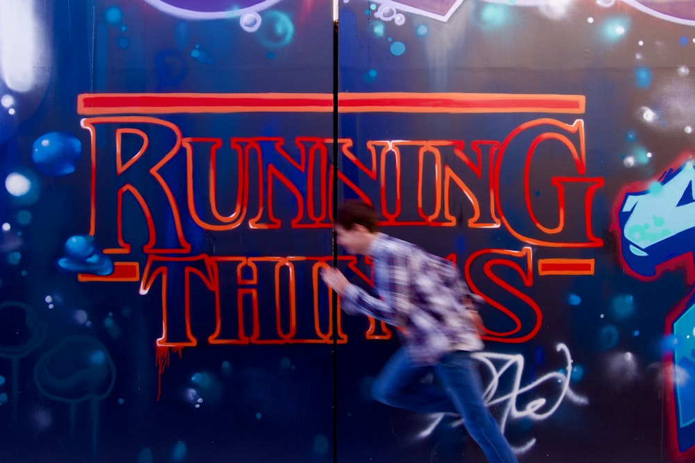 a man is running in front of a wall with graffiti