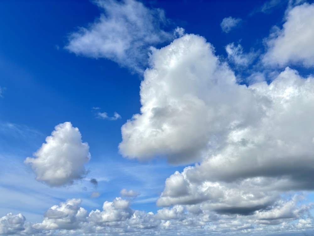 a beach with a boat in the water and clouds in the sky