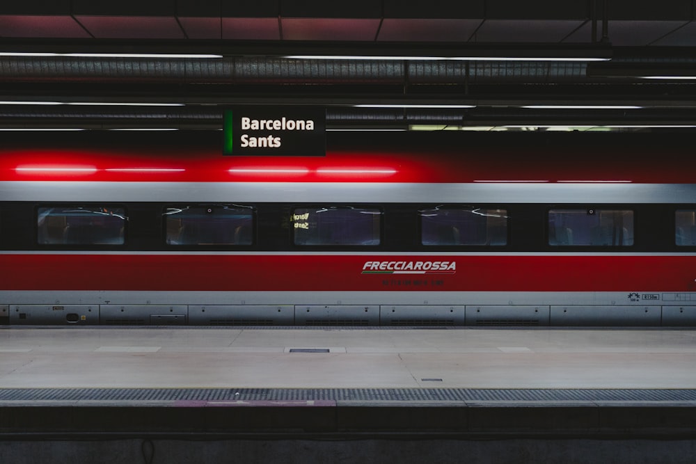 a red and silver train parked at a train station