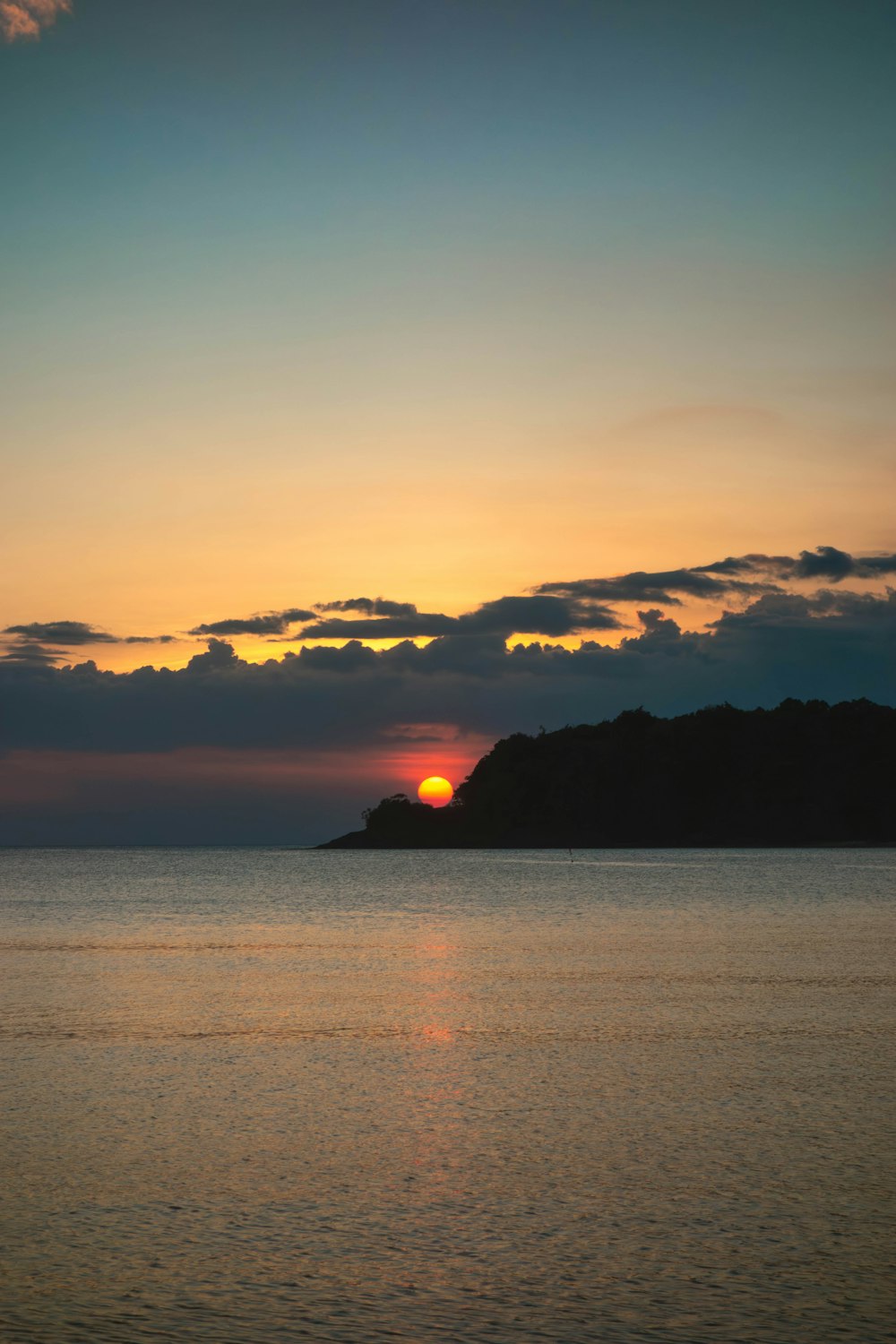 the sun is setting over a small island in the middle of the ocean