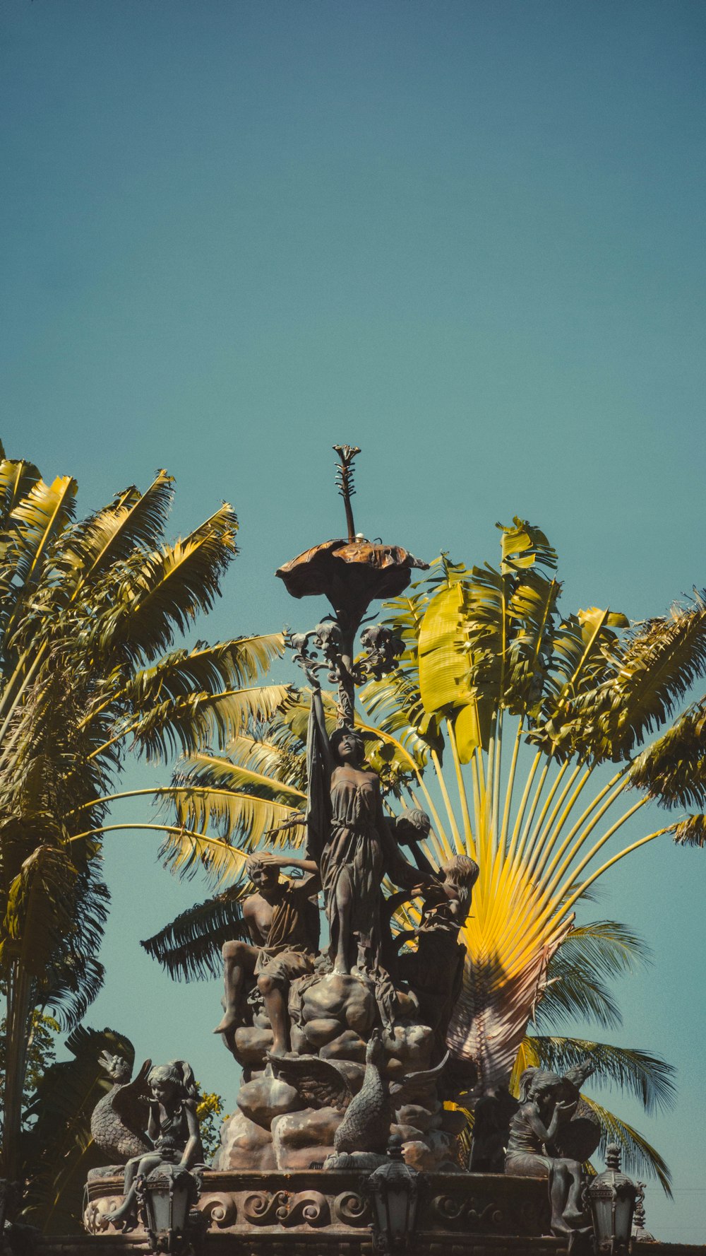 a statue with a cross on top of it surrounded by palm trees