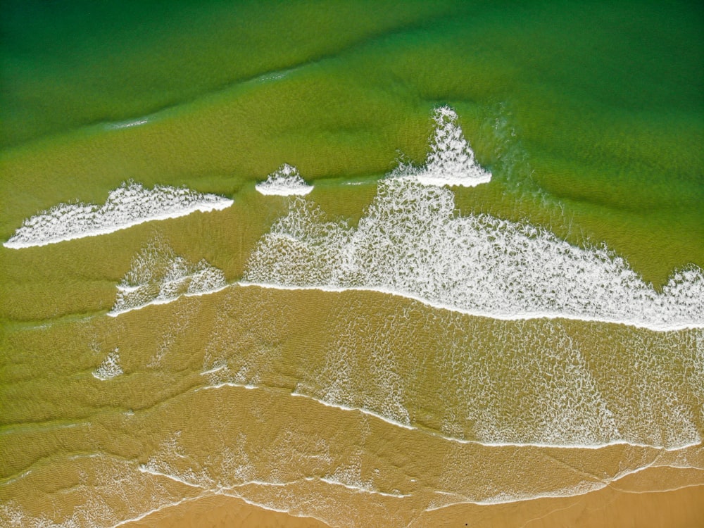 an aerial view of a sandy beach with waves