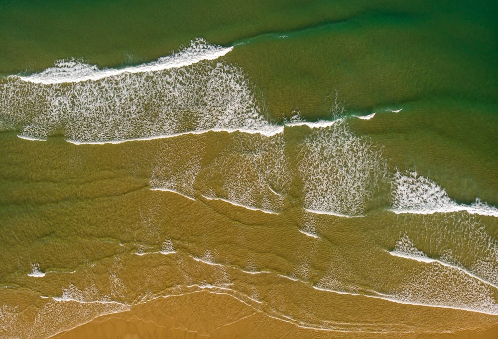 an aerial view of a sandy beach with waves