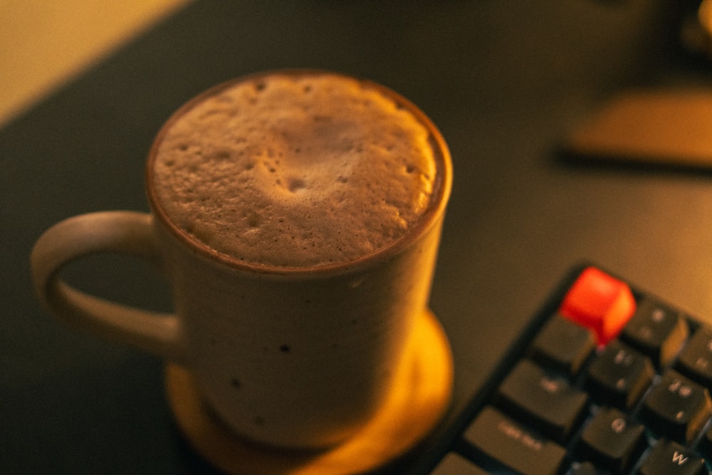 a cup of coffee sitting next to a keyboard