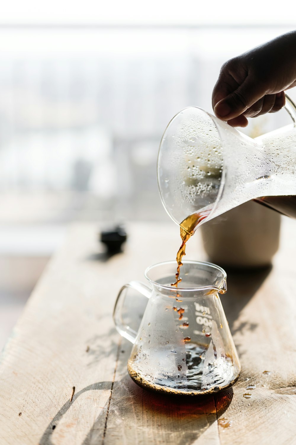 a person pours coffee into a glass pitcher