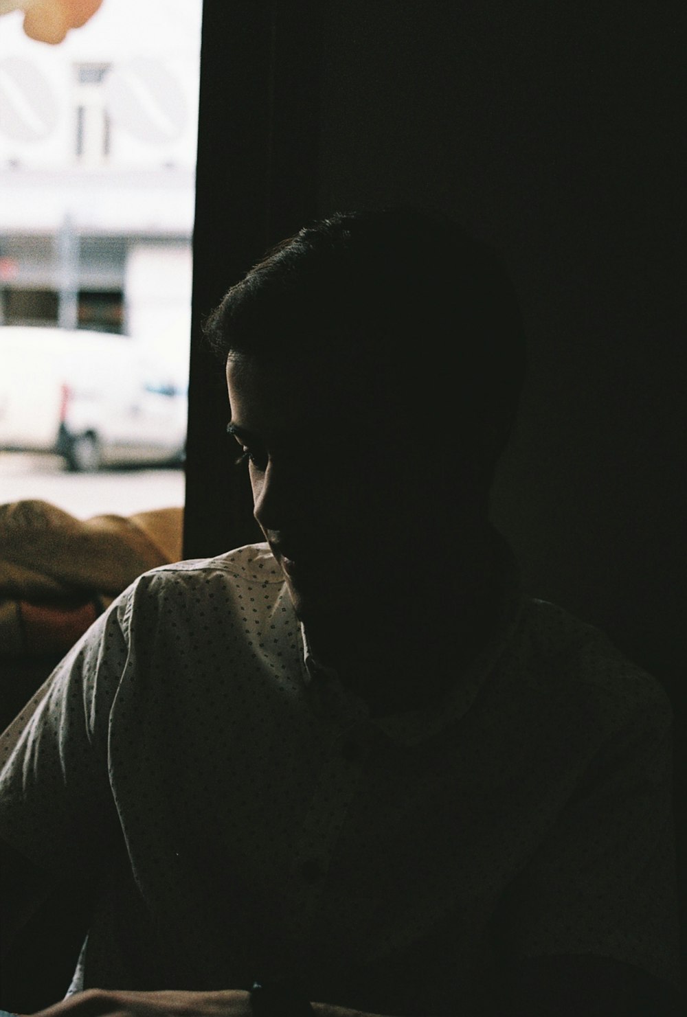 a man sitting in front of a window in a dark room