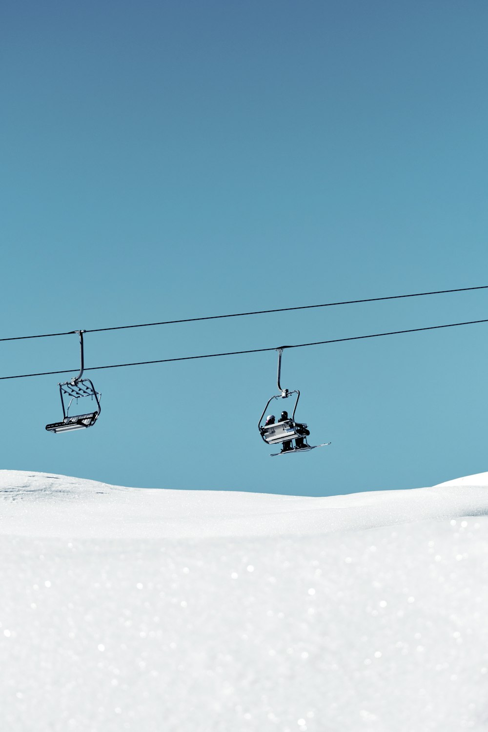 um teleférico com dois esquiadores subindo uma colina nevada