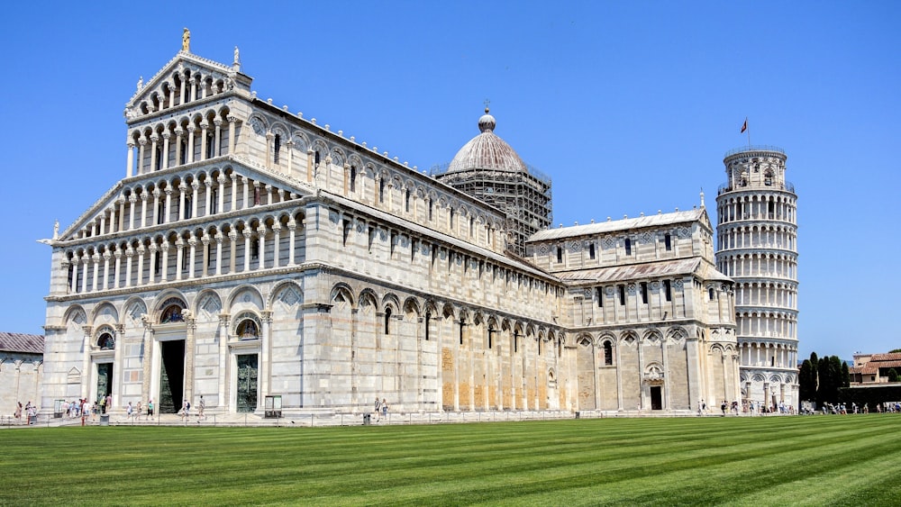 a large building with a tall tower next to a lush green field