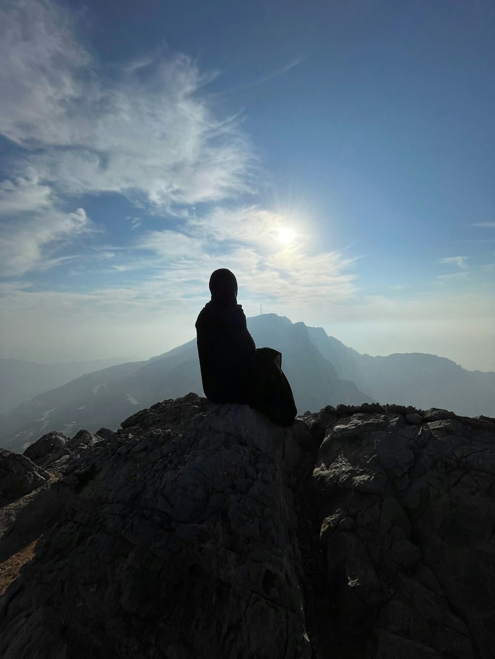 una persona seduta in cima a una montagna che guarda il cielo