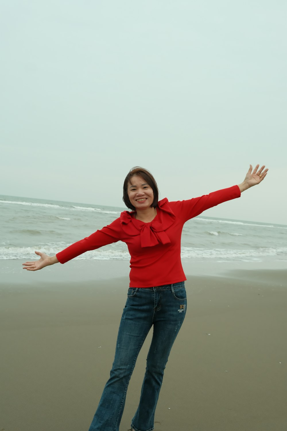 a woman standing on a beach with her arms outstretched