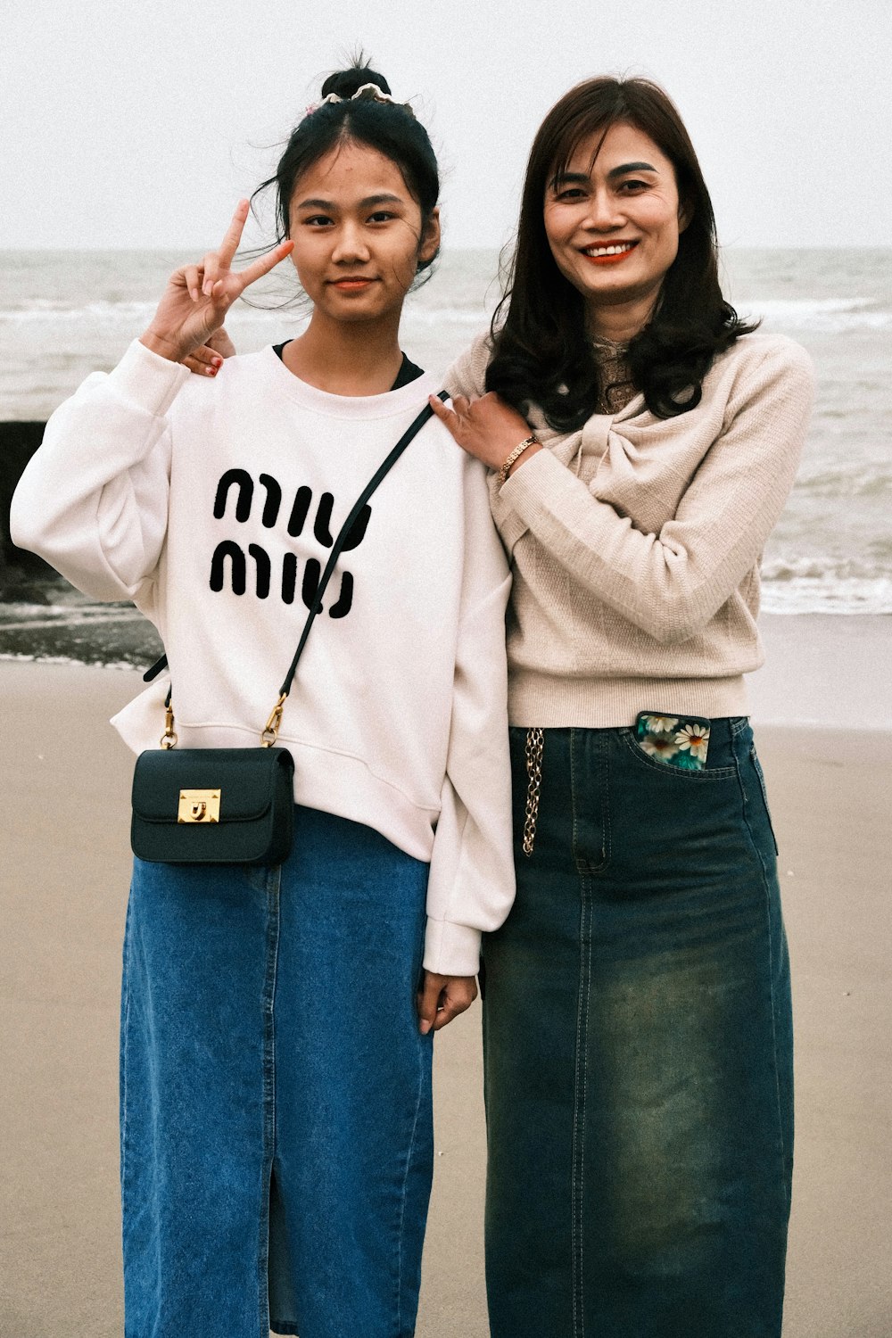 two women standing next to each other on a beach