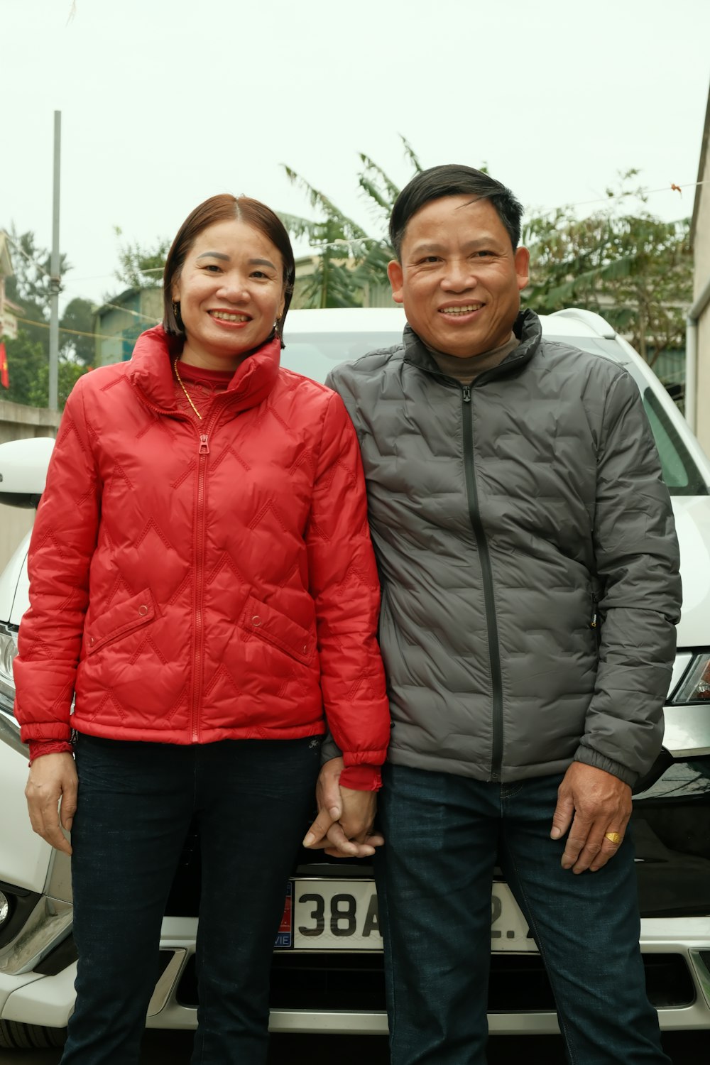 a man and woman standing in front of a car