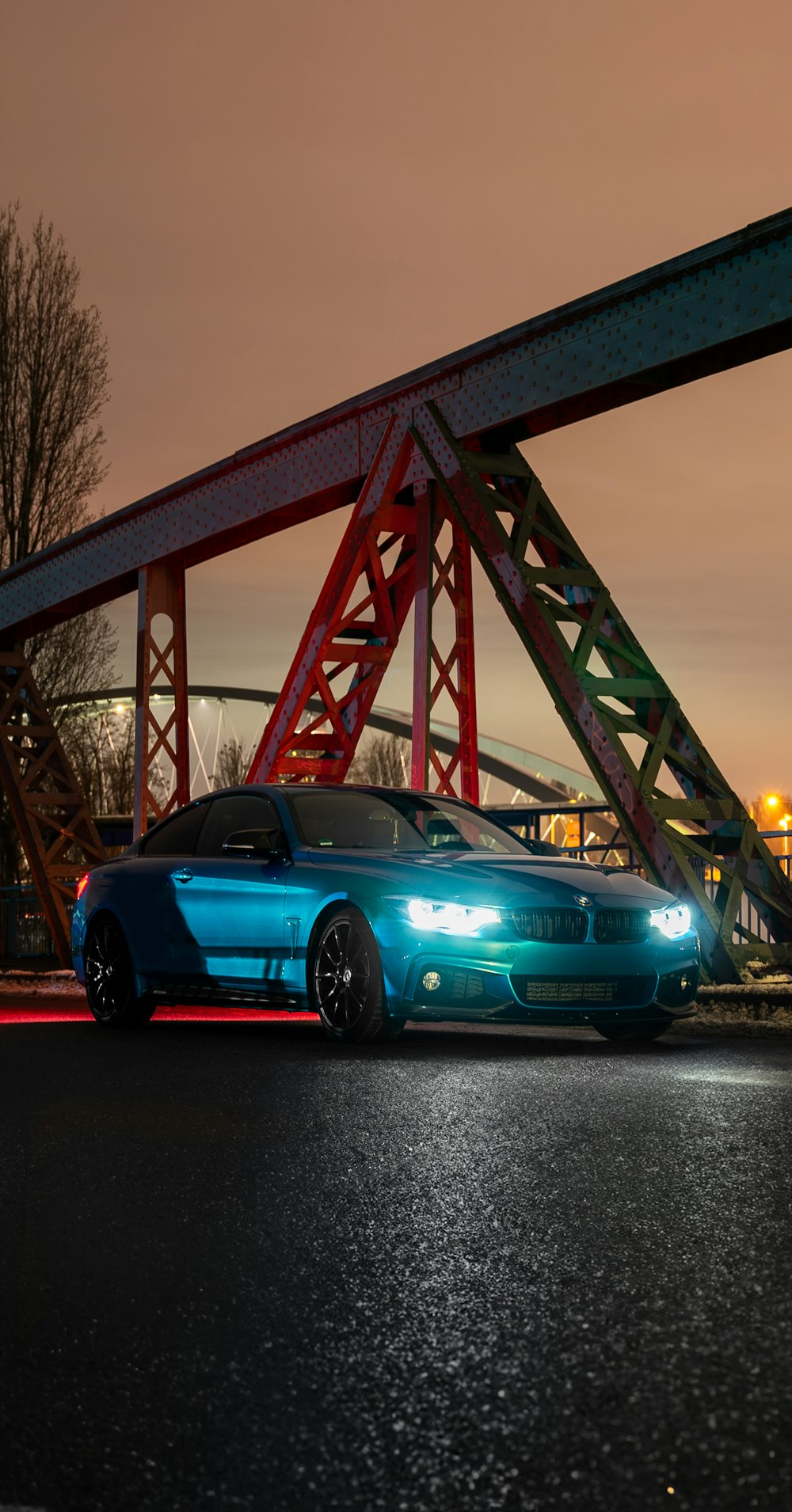 a blue car parked in front of a red bridge