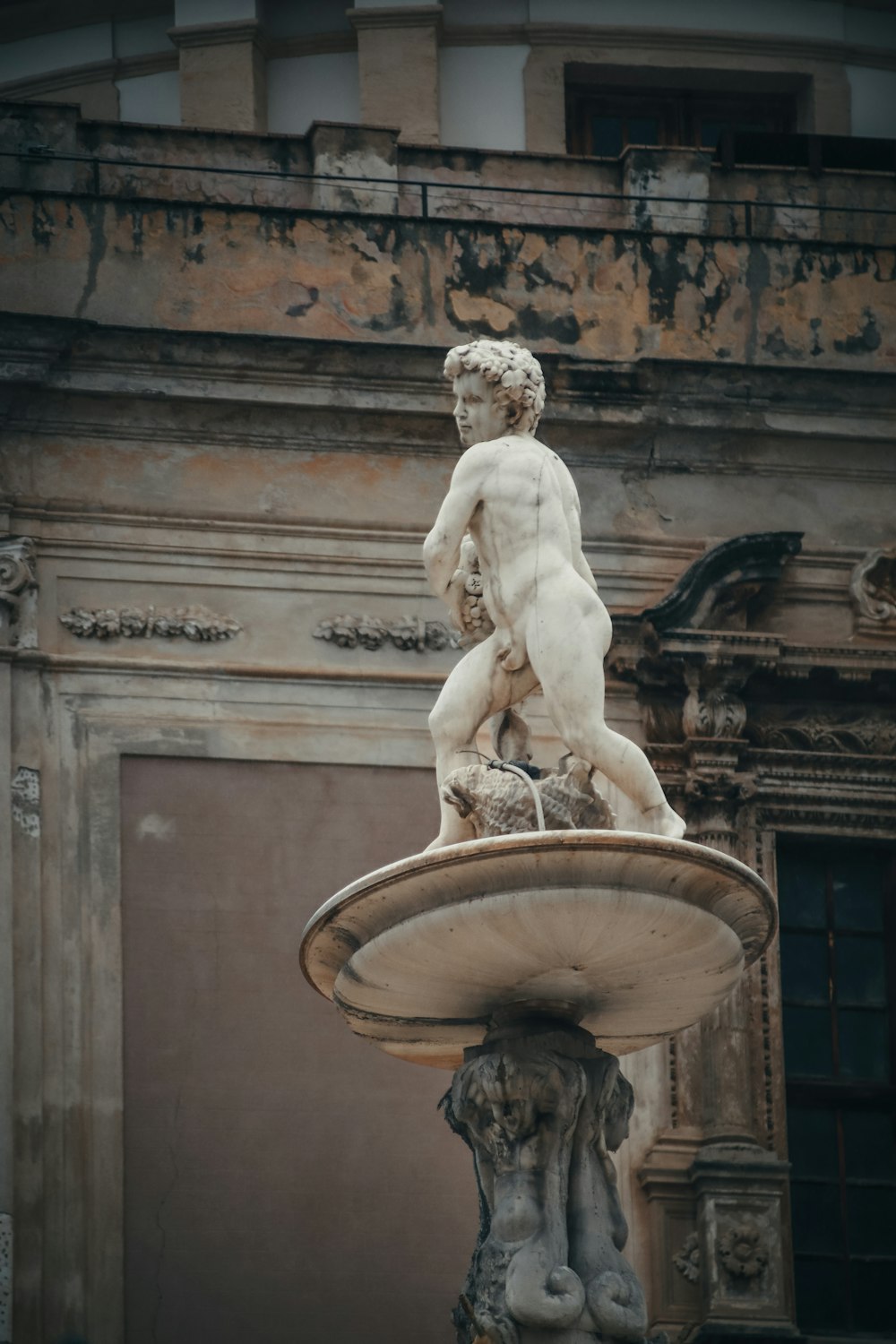 a statue of a naked man on top of a fountain