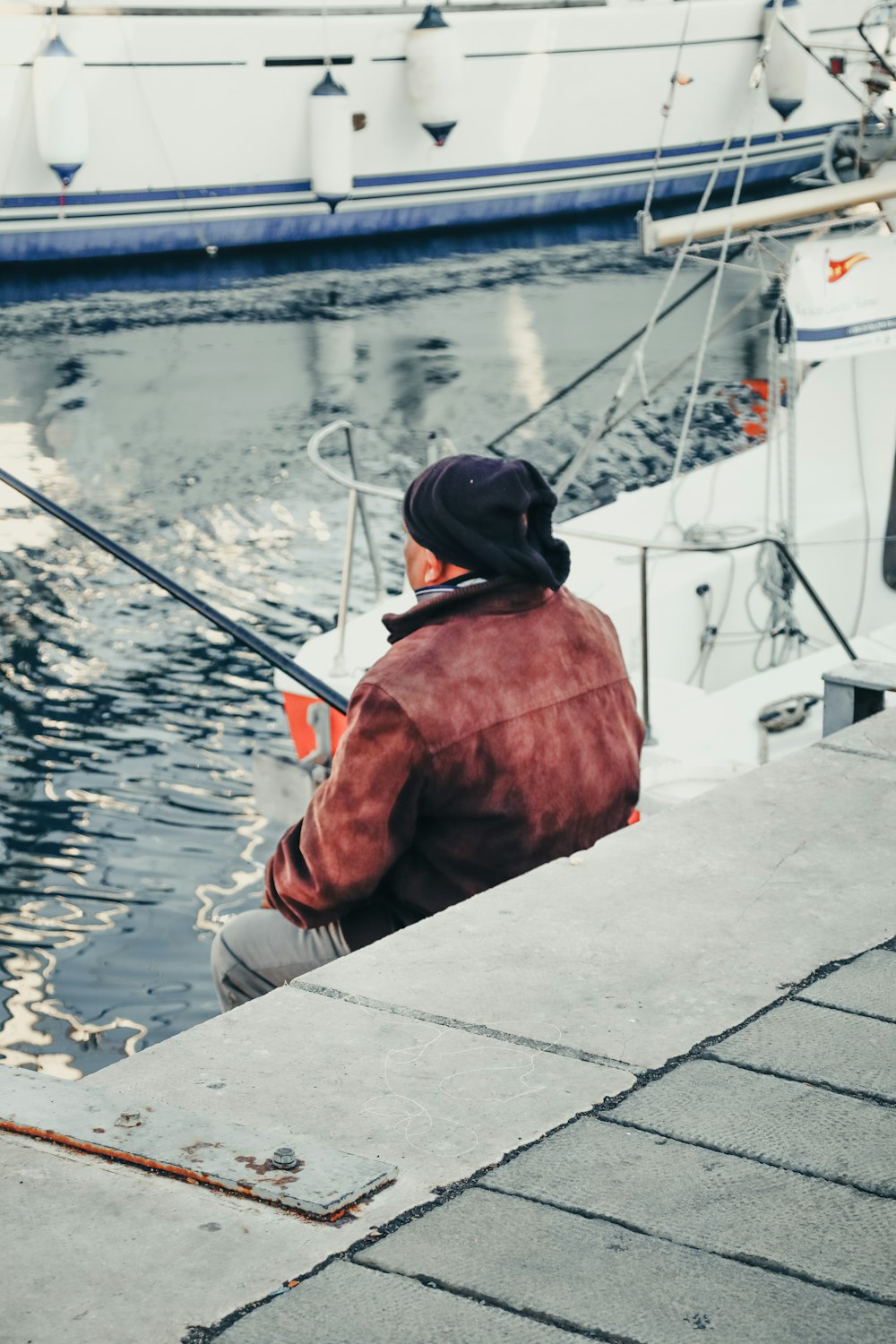 a man sitting on a dock with a fishing pole