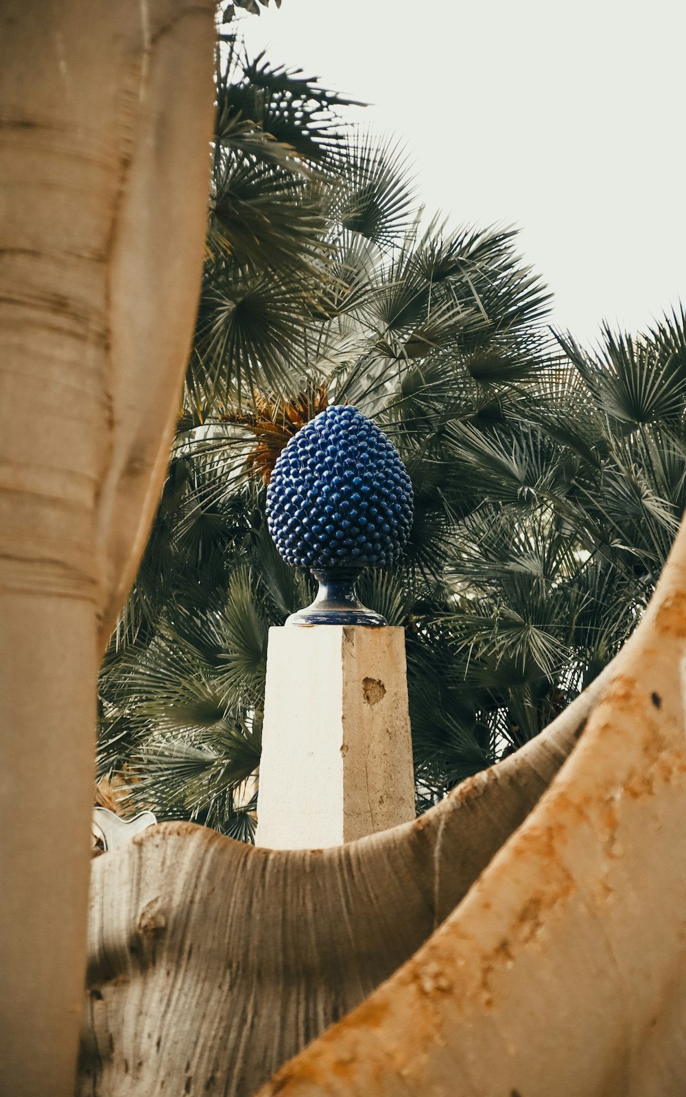 une boule bleue posée sur un pilier de ciment