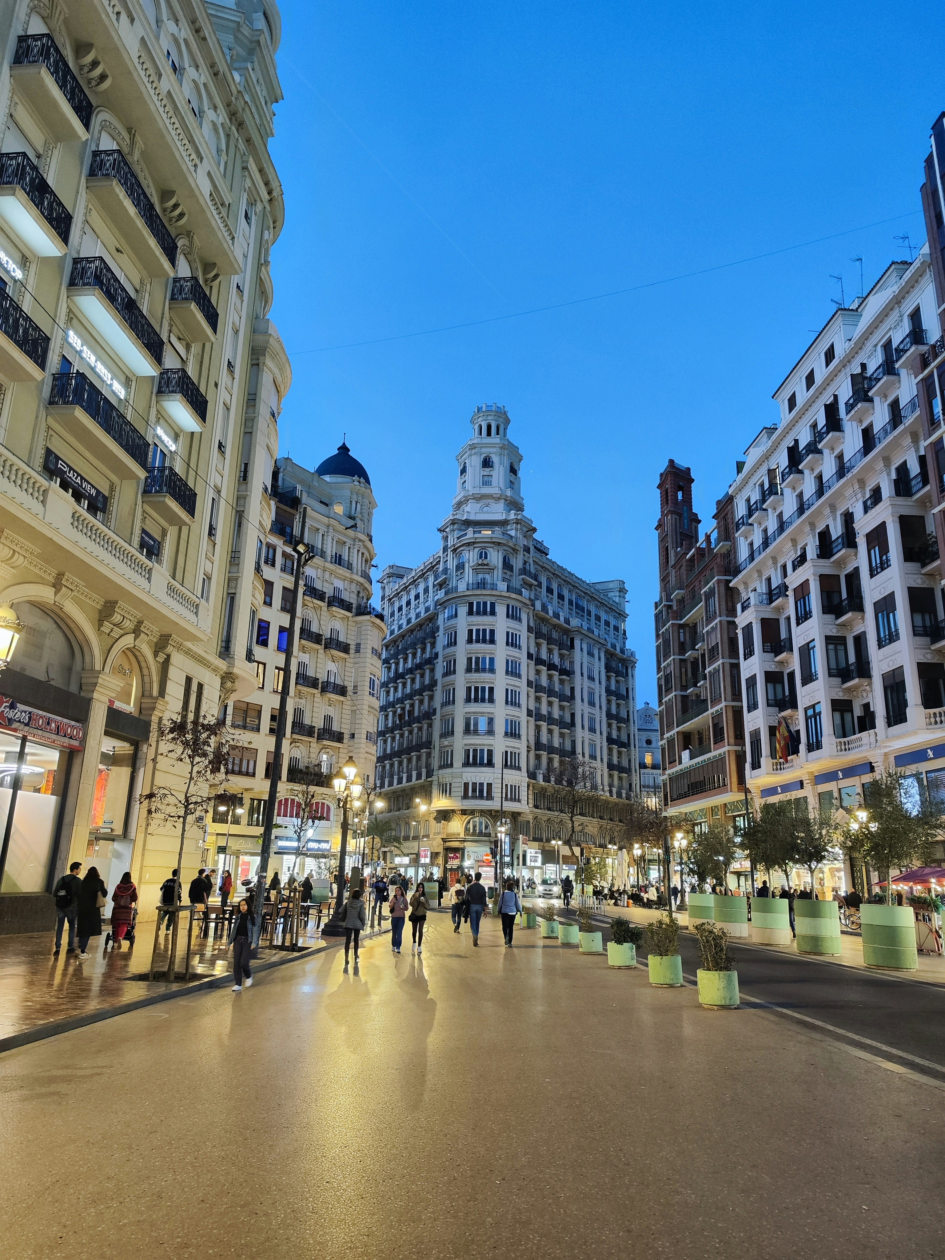 a group of people walking down a street next to tall buildings