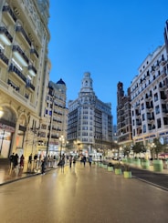 a group of people walking down a street next to tall buildings