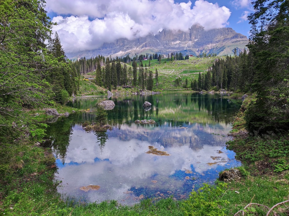 Un lago de montaña rodeado de árboles y nubes