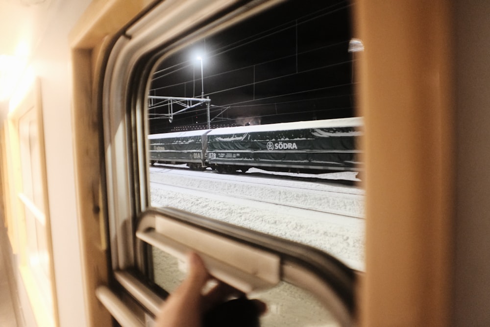 a person looking out a train window at a train