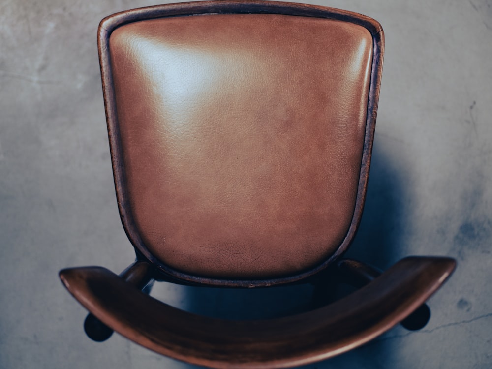 a brown leather chair sitting on top of a cement floor