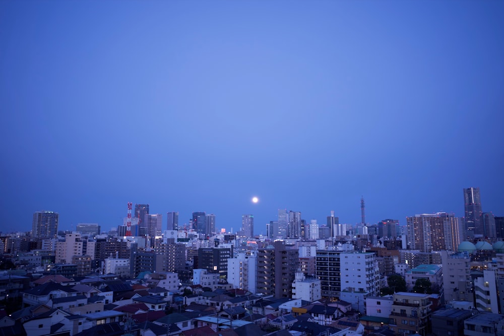 a view of a city at night with a full moon in the sky