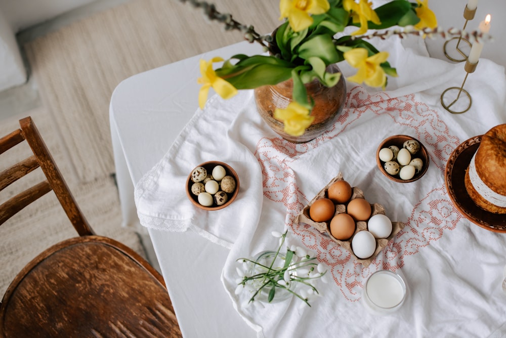 a table topped with eggs next to a vase of flowers