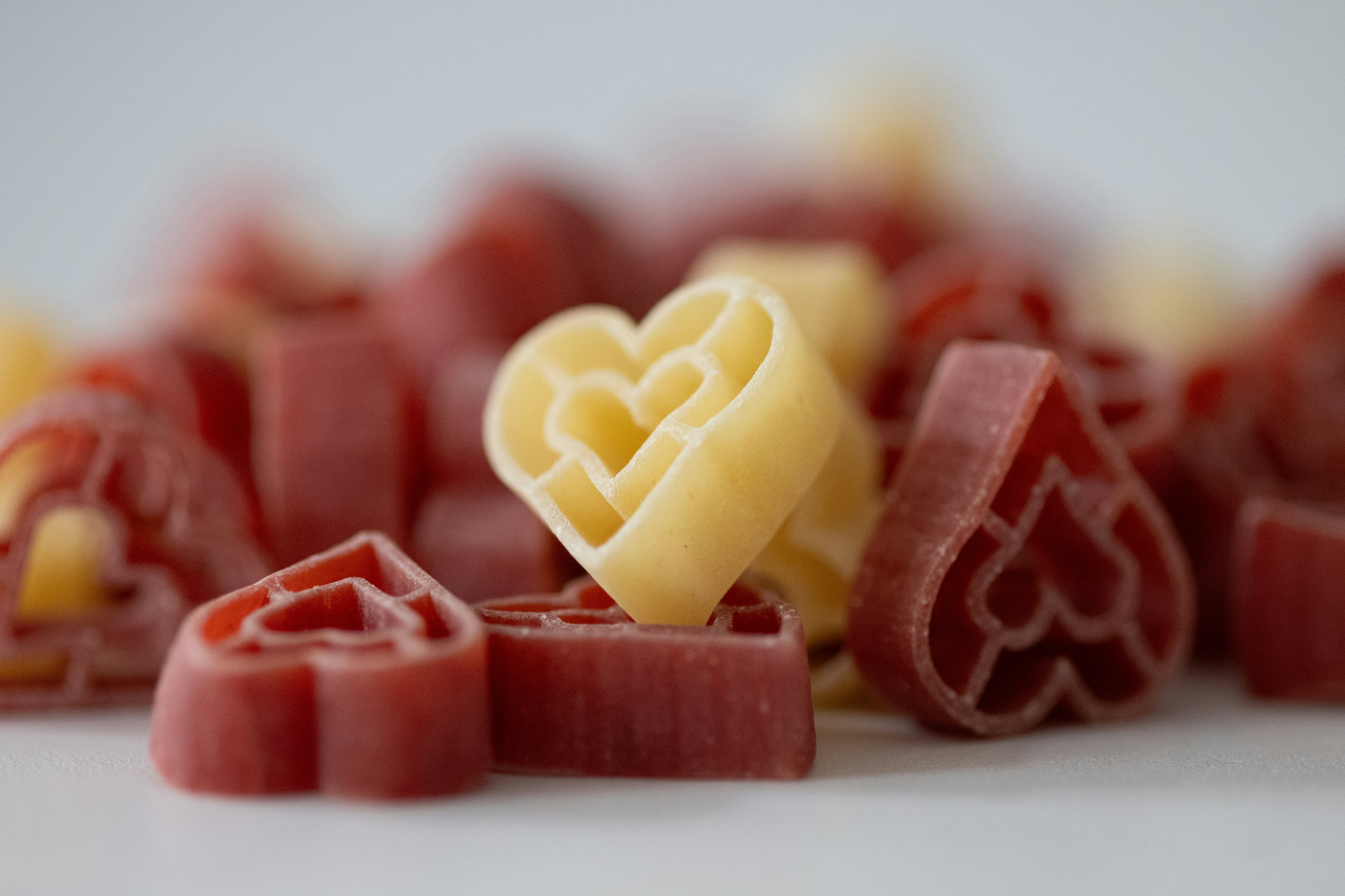a couple of pieces of food sitting on top of a table, Twirling strands of pasta lovingly arranged in the shape of a heart, a delicious declaration of culinary affection.
