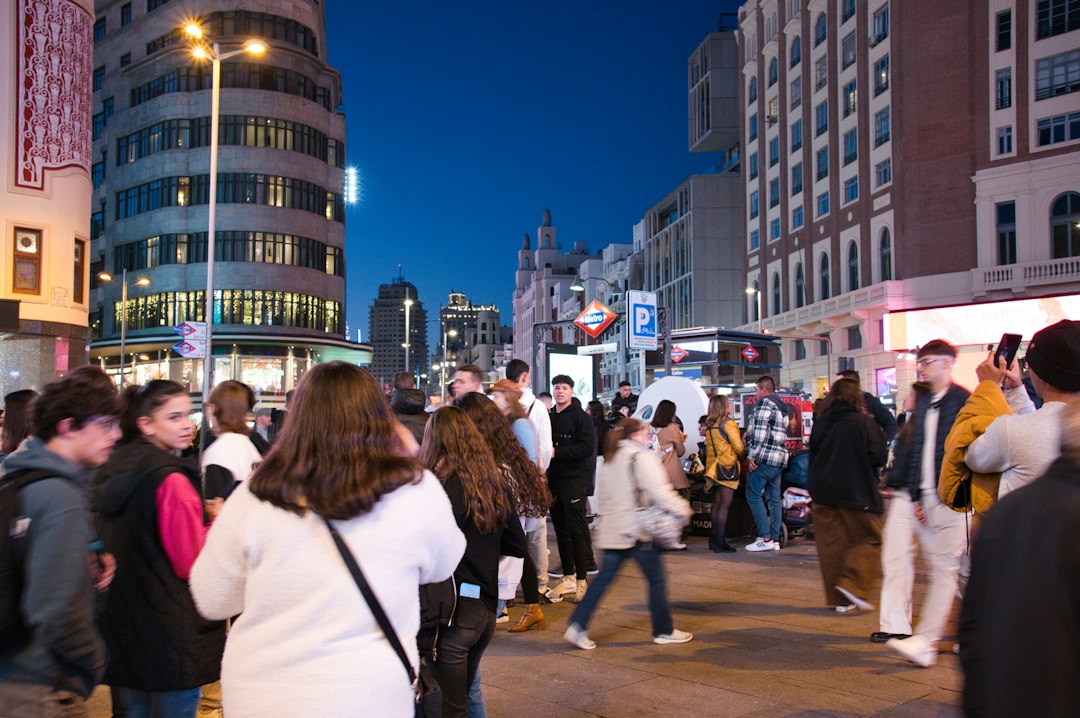 a crowd of people walking down a street next to tall buildings