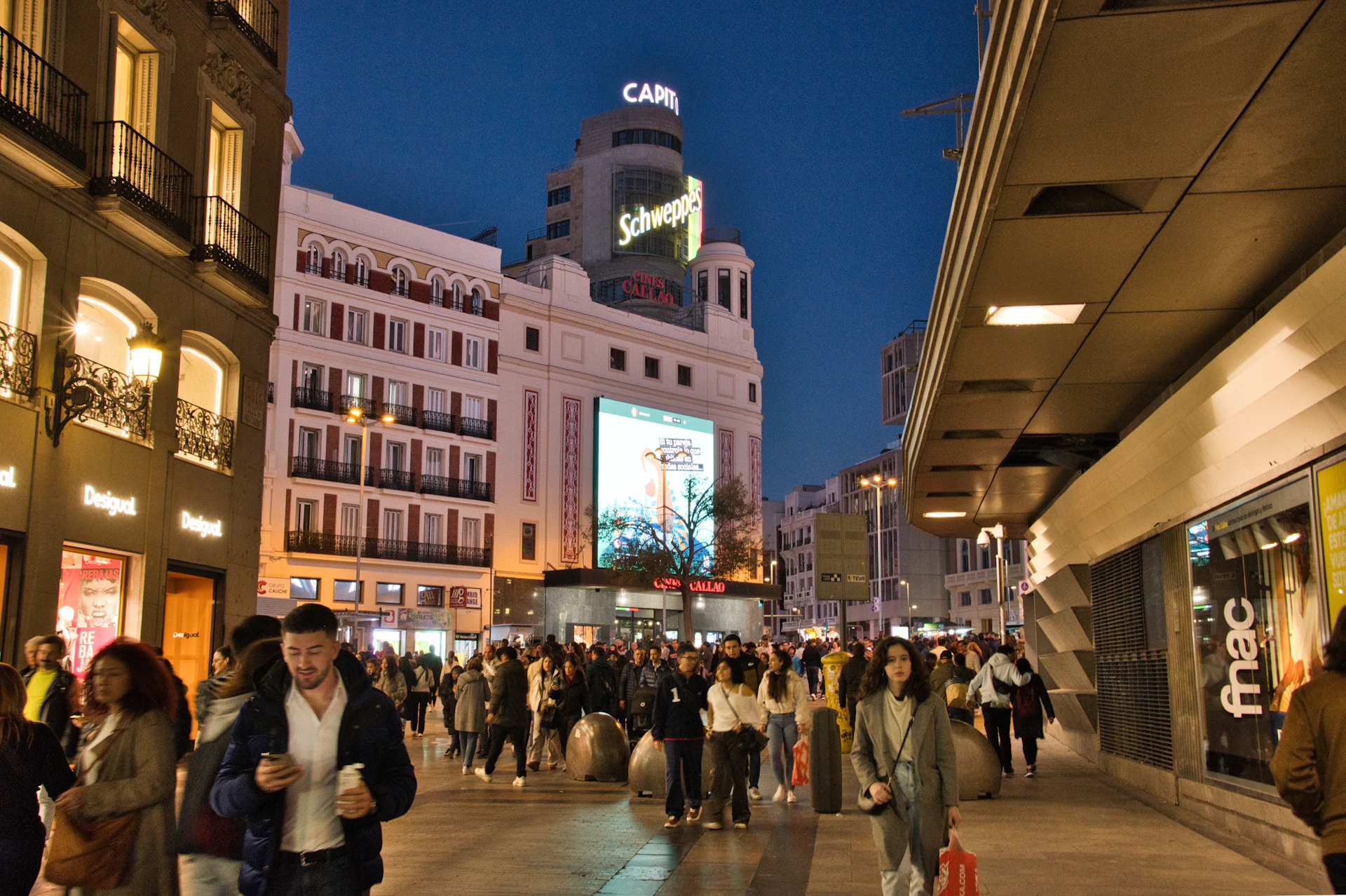 a crowd of people walking down a street next to tall buildings