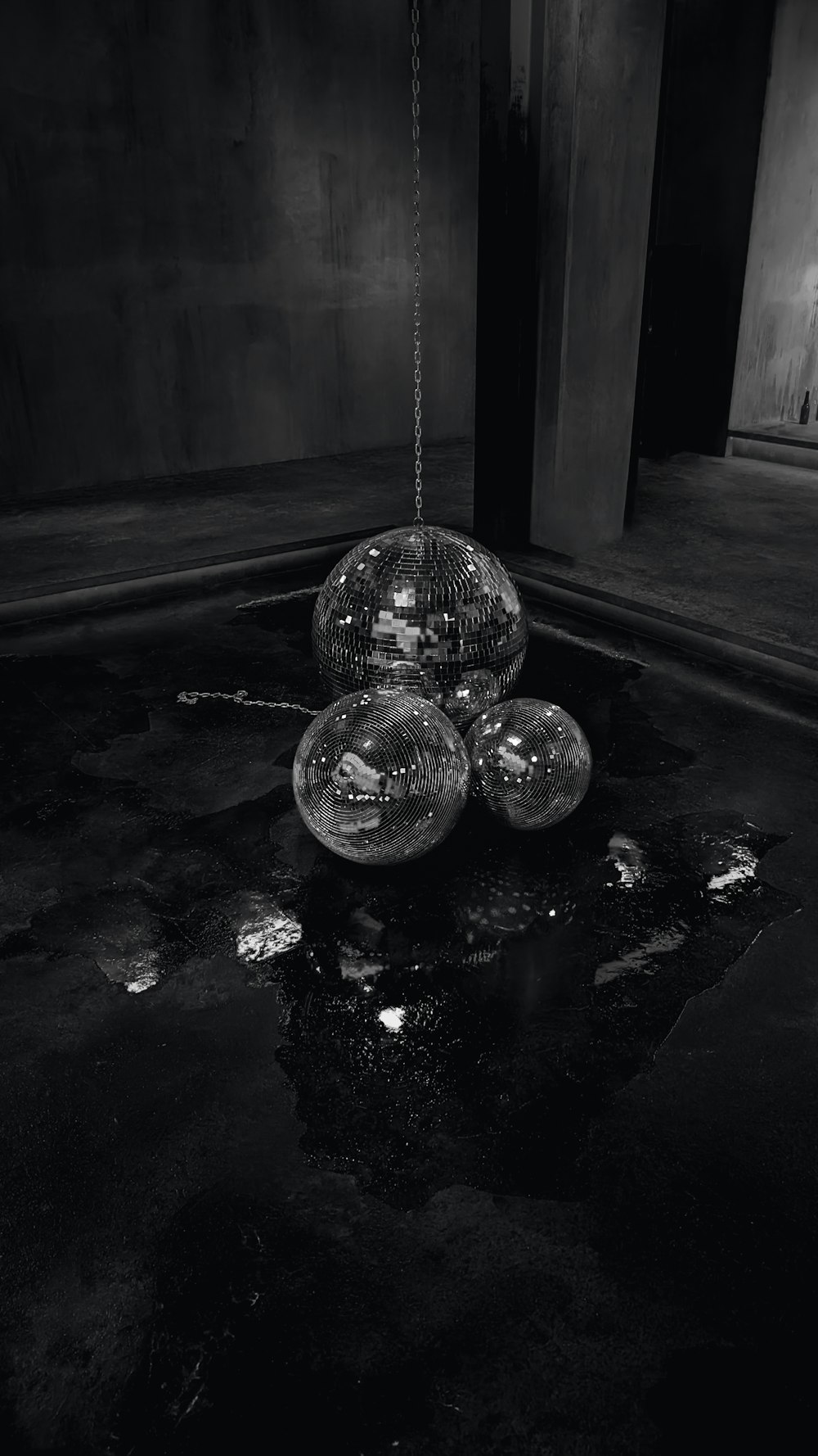 a black and white photo of three balls hanging from a chain