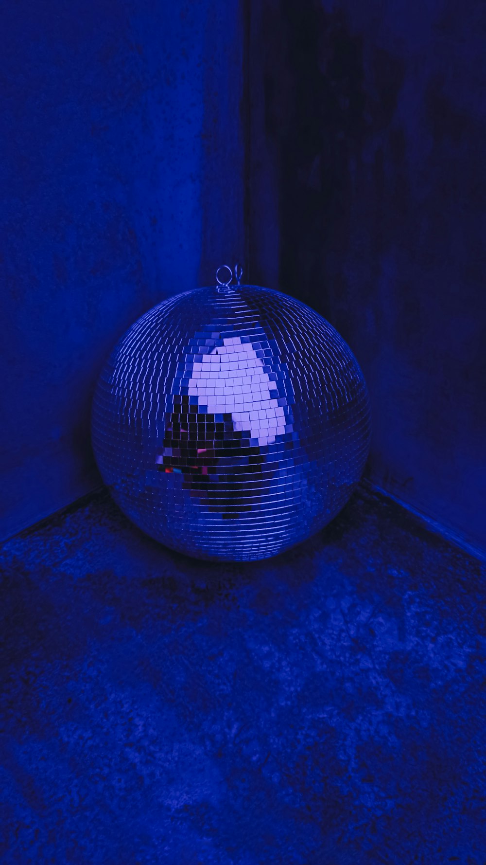 una bola de discoteca sentada en el suelo frente a una pared