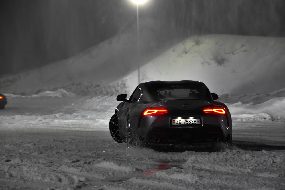 a couple of cars driving down a snow covered road