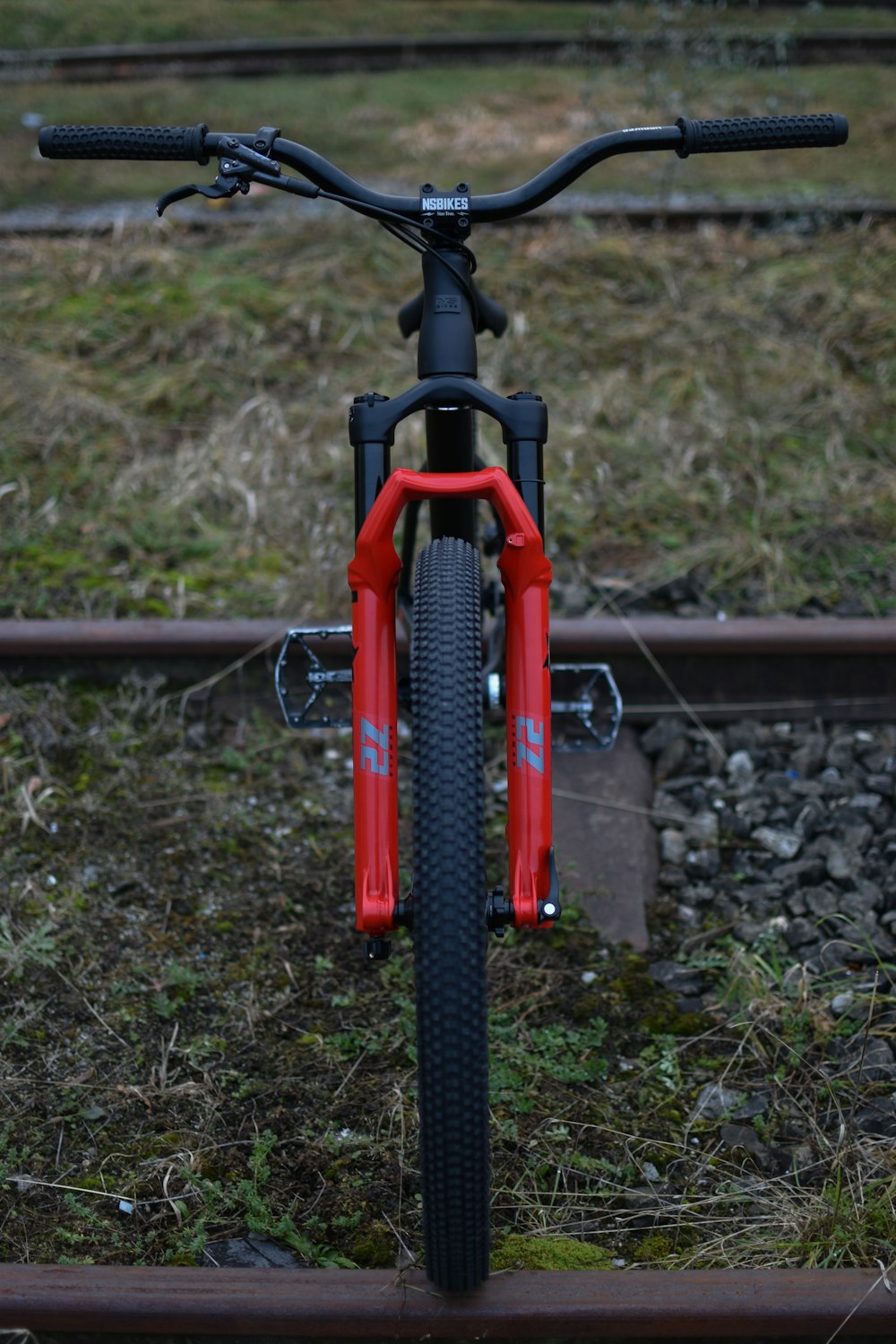 a red and black bike parked on a train track