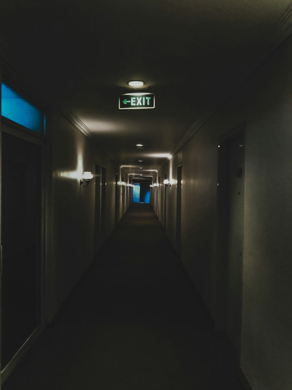 a long hallway with a exit sign on the wall