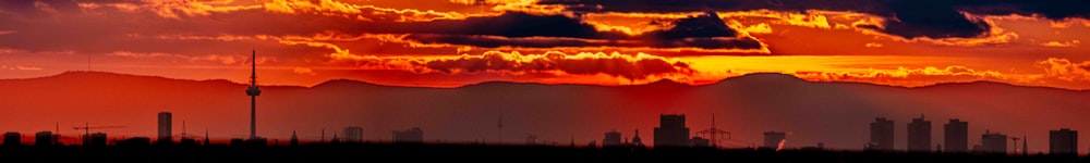 the sun is setting over a city with mountains in the background