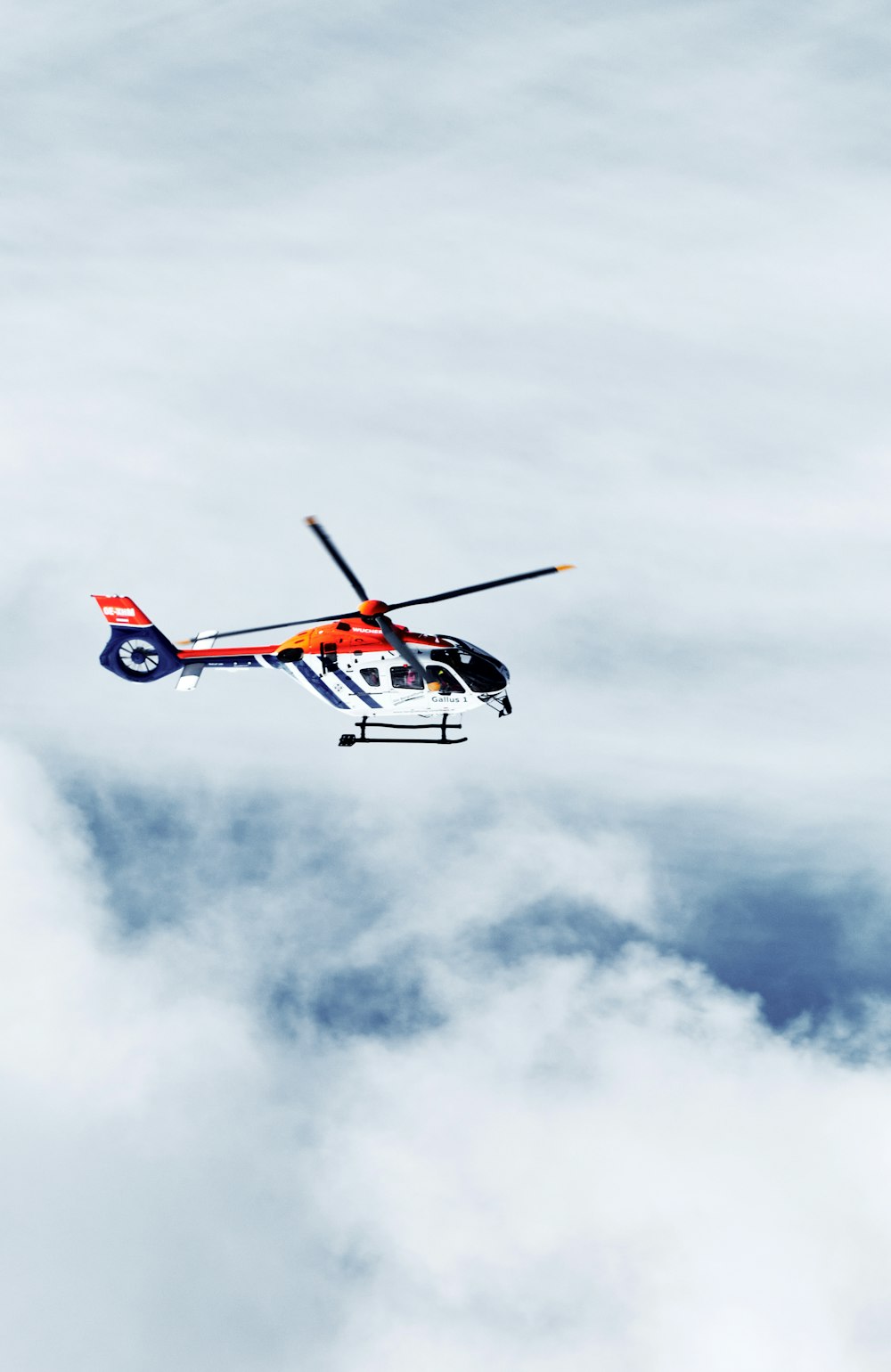 a helicopter flying through a cloudy blue sky