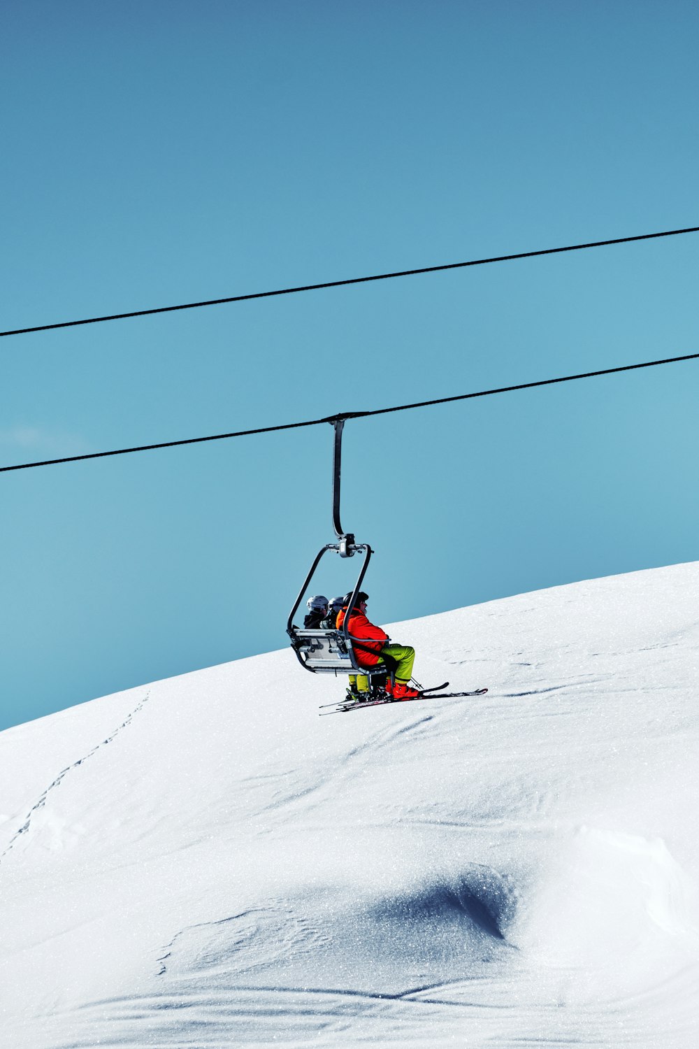 a person riding a ski lift down a snow covered slope