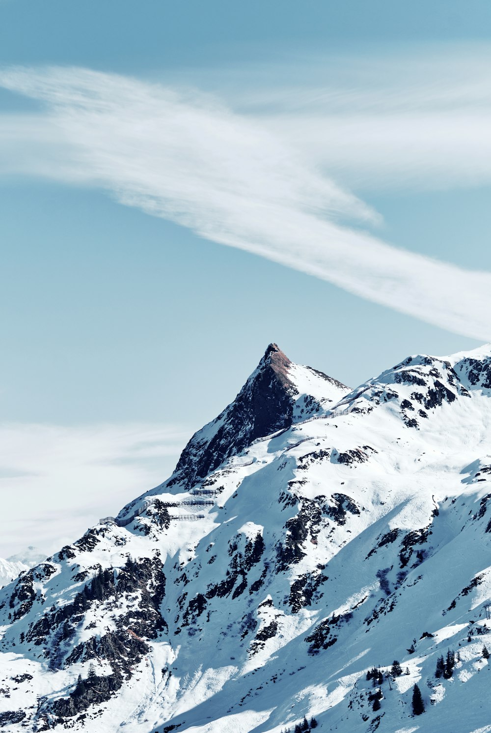 a snow covered mountain with a single cloud in the sky