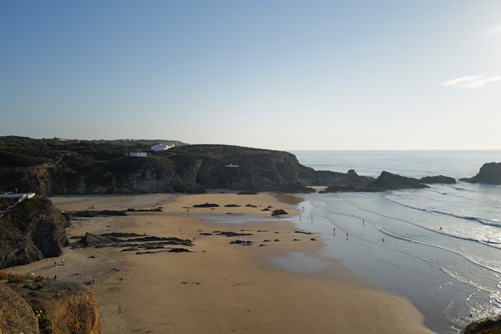 a sandy beach next to the ocean under a blue sky