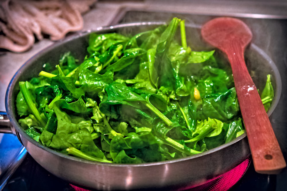 a pan filled with green vegetables on top of a stove