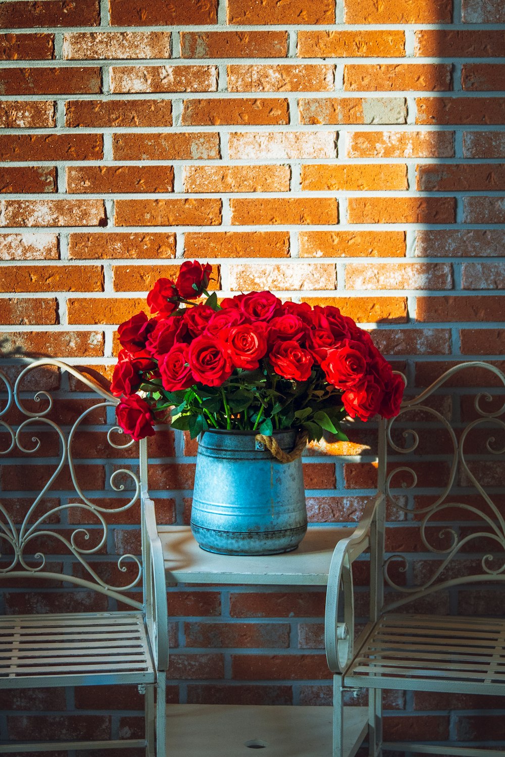 a blue vase filled with red roses sitting on top of a table