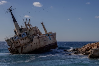 an old ship sitting in the middle of the ocean