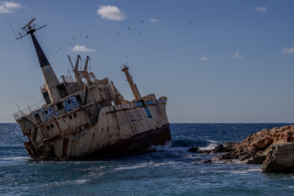 an old ship sitting in the middle of the ocean