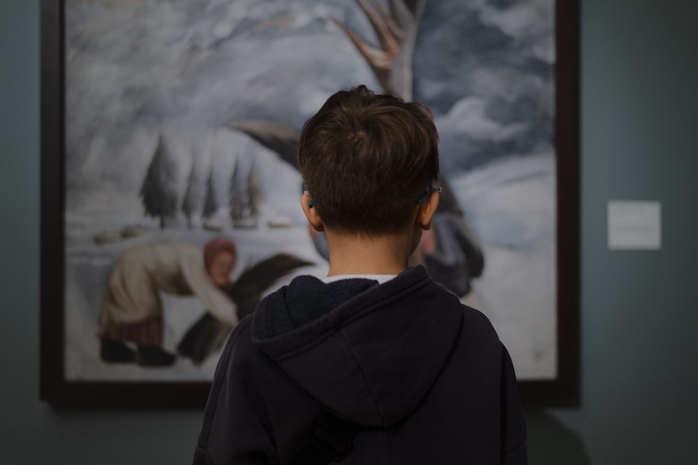 un jeune garçon debout devant un tableau
