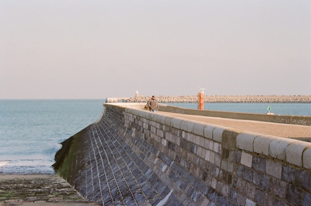 a man riding a skateboard on the side of a wall next to the ocean