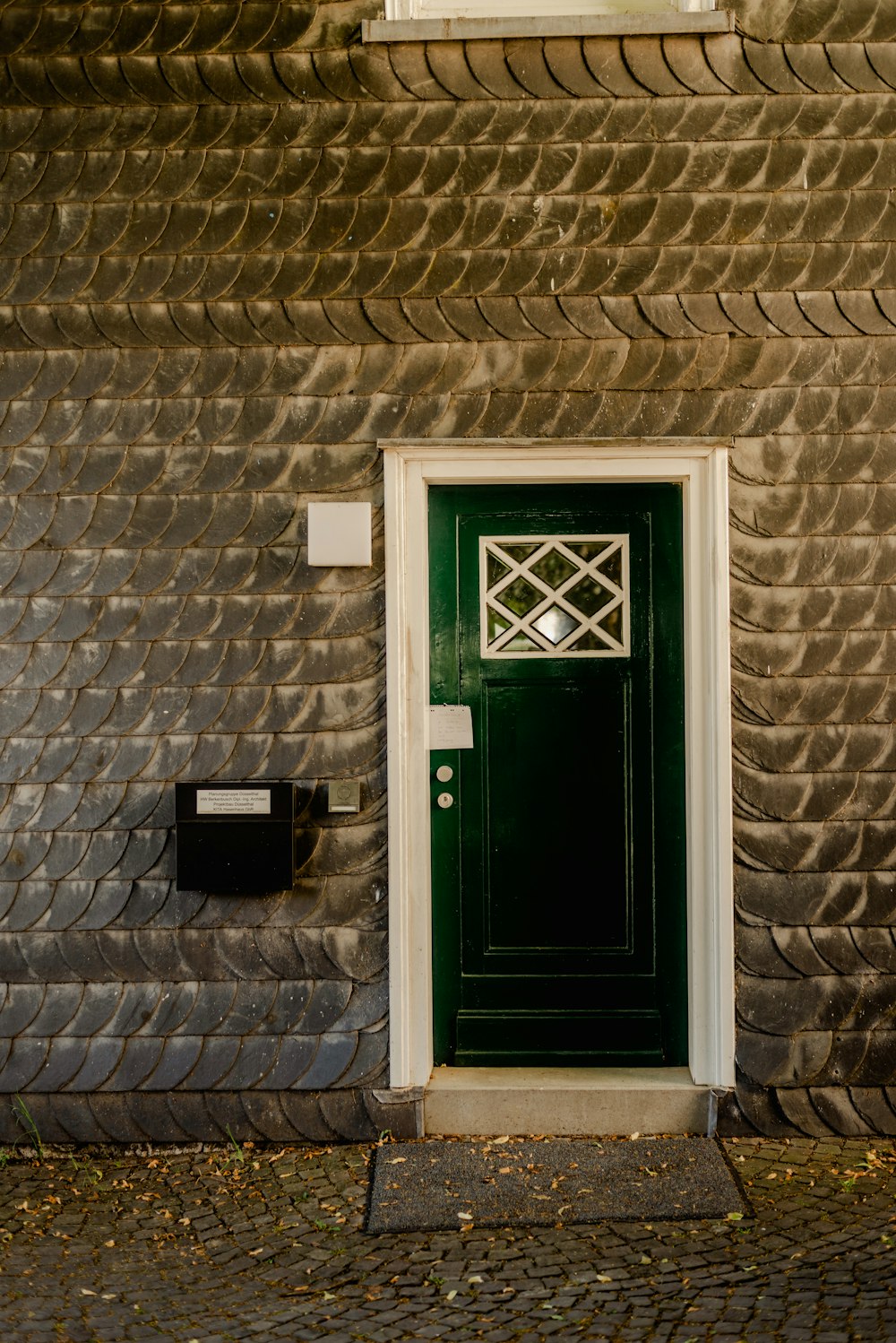 a green door on the side of a brick building